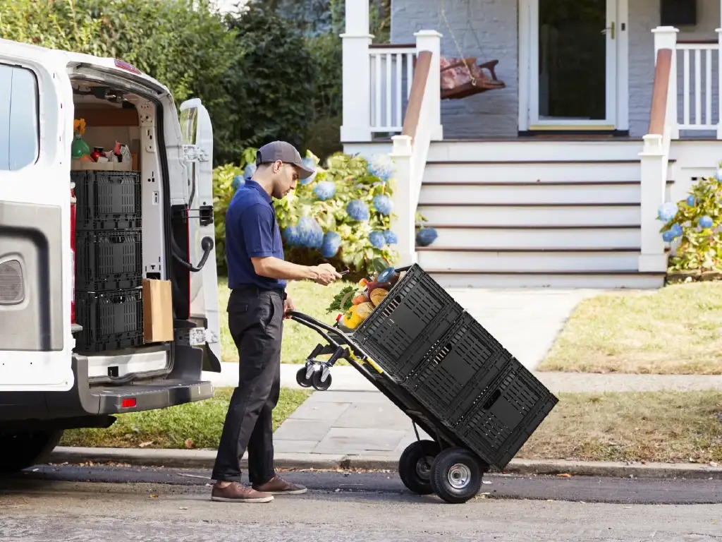 An image of a delivery man pushing a cart full of Rehrig pallets filled with groceries