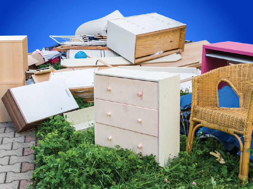 A photo of a dresser a chair and other furniture and trash littered on a sidewalk.webp