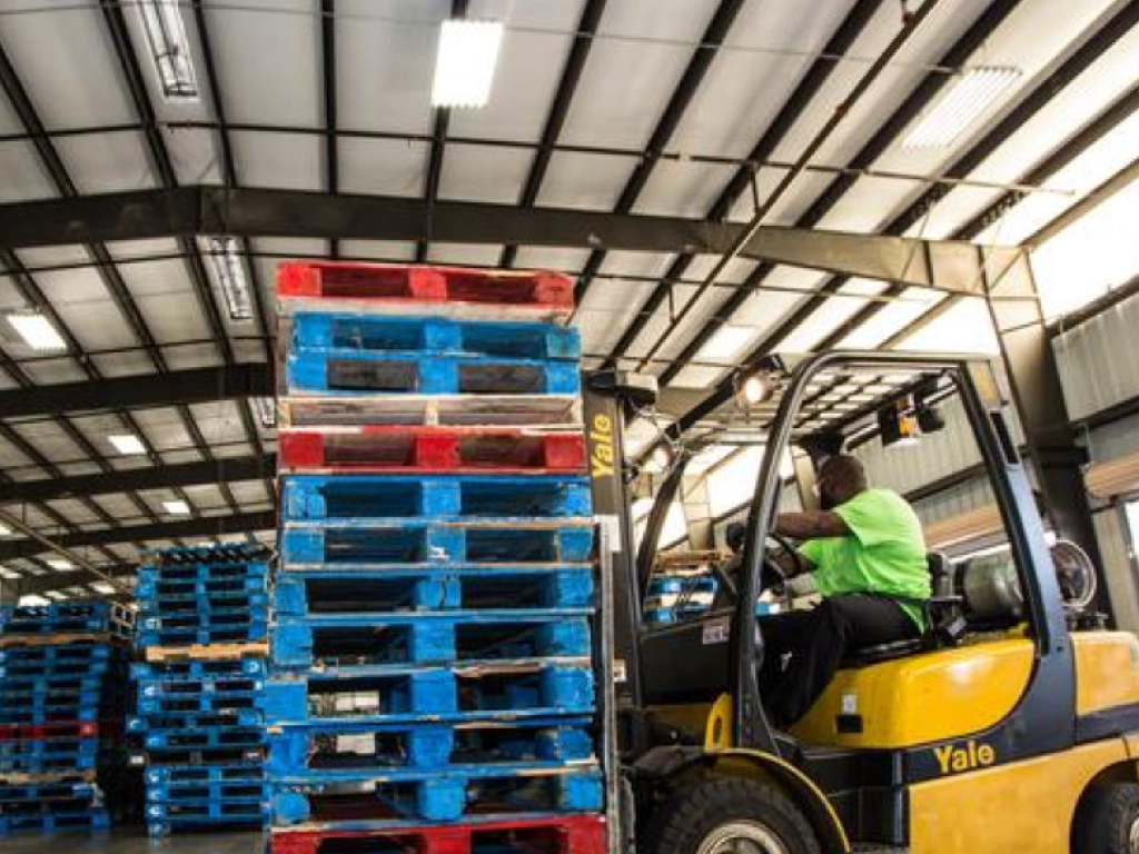 A photo of a forklift moving pallets in a warehouse